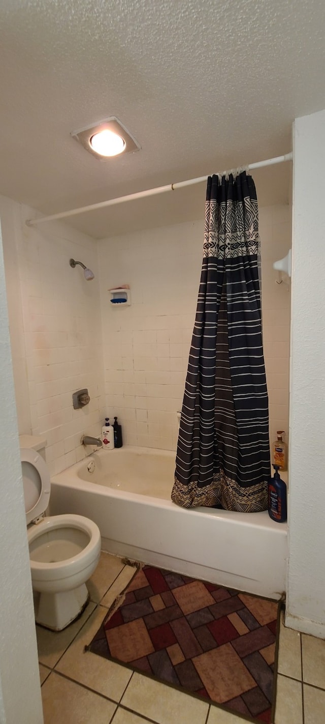 bathroom with a textured ceiling, shower / bath combination with curtain, toilet, and tile patterned floors