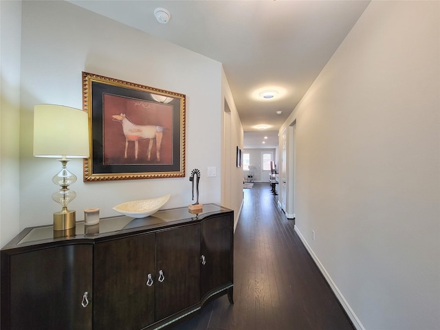 hall with dark wood-style floors and baseboards