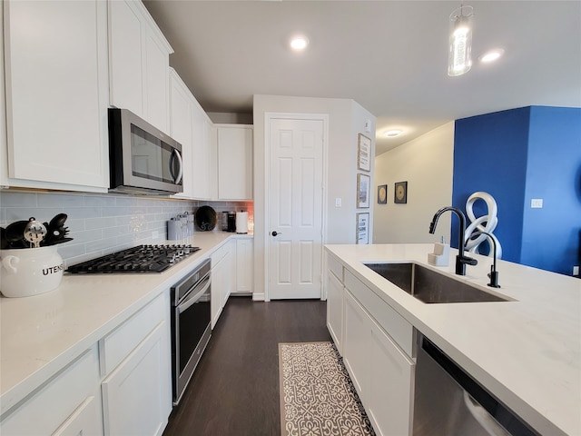 kitchen featuring backsplash, stainless steel appliances, sink, white cabinets, and dark hardwood / wood-style flooring