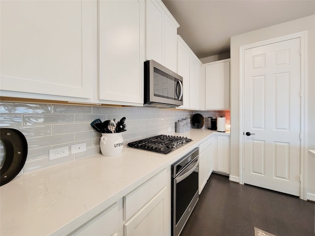 kitchen with dark hardwood / wood-style flooring, tasteful backsplash, white cabinetry, light stone counters, and stainless steel appliances