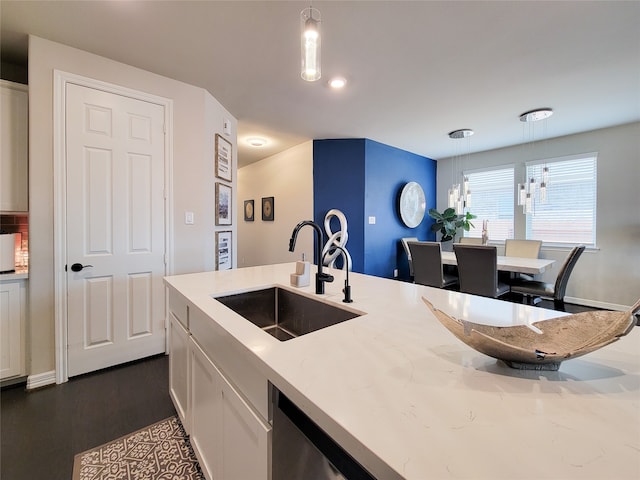 kitchen with dark hardwood / wood-style floors, sink, light stone countertops, white cabinets, and hanging light fixtures