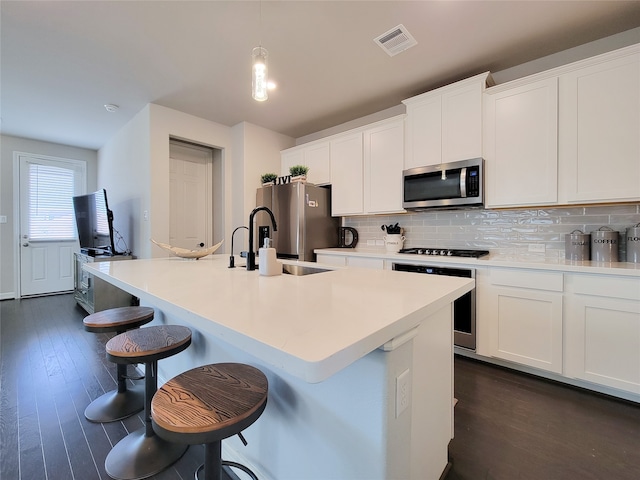 kitchen featuring stainless steel appliances, decorative backsplash, dark hardwood / wood-style flooring, and hanging light fixtures