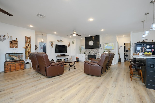 living area featuring light wood-style flooring, recessed lighting, a fireplace, visible vents, and a ceiling fan