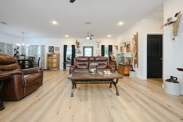 living room featuring light wood-type flooring, visible vents, and ceiling fan with notable chandelier