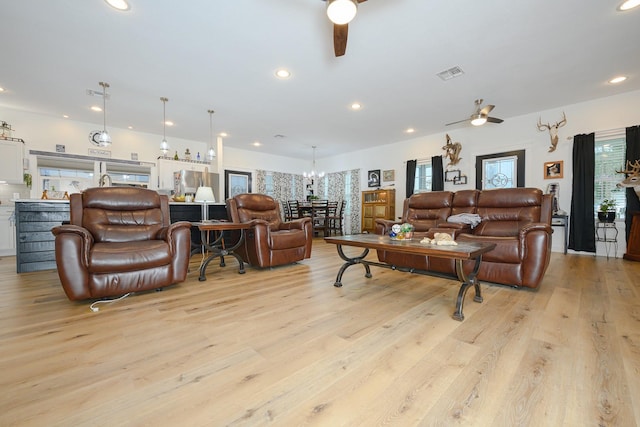 living area featuring ceiling fan with notable chandelier, light wood-style flooring, visible vents, and recessed lighting