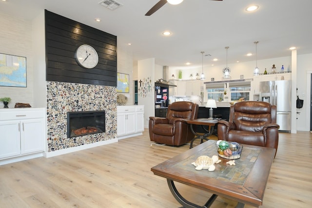 living area featuring ceiling fan, recessed lighting, a fireplace, visible vents, and light wood-style floors