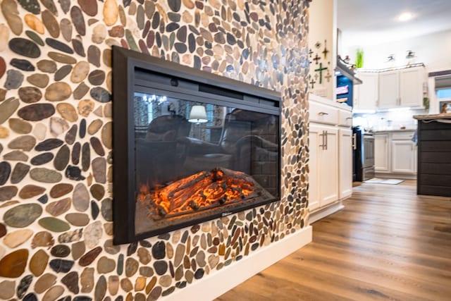 details with a glass covered fireplace, electric stove, recessed lighting, and wood finished floors