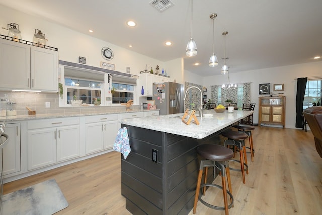 kitchen with tasteful backsplash, white cabinetry, visible vents, and stainless steel fridge with ice dispenser