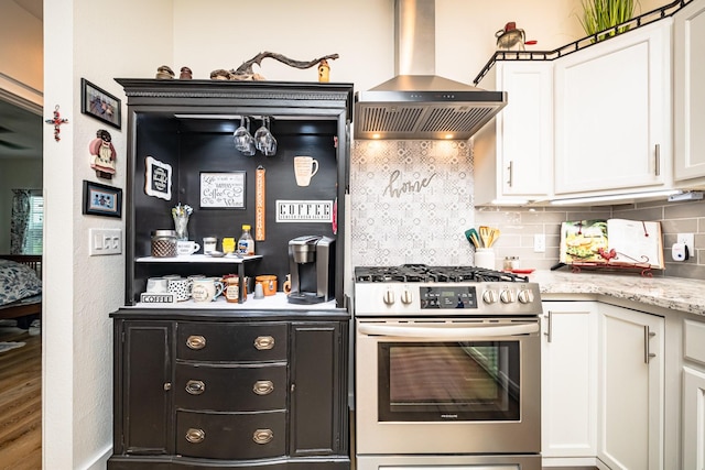 kitchen with stainless steel gas stove, backsplash, white cabinets, and range hood