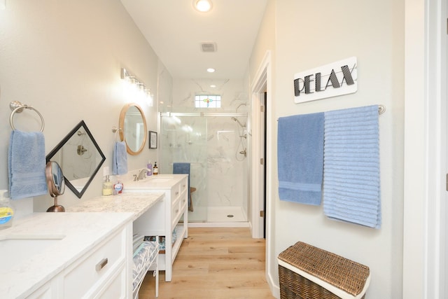 full bathroom with recessed lighting, a marble finish shower, wood finished floors, and vanity