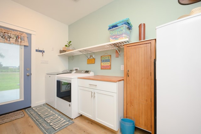 washroom with light wood finished floors, cabinet space, and washing machine and clothes dryer