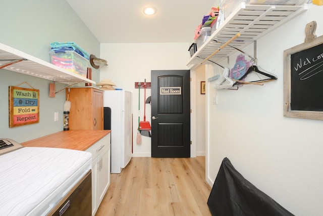 kitchen featuring white cabinets, light countertops, light wood-style flooring, and washer and dryer