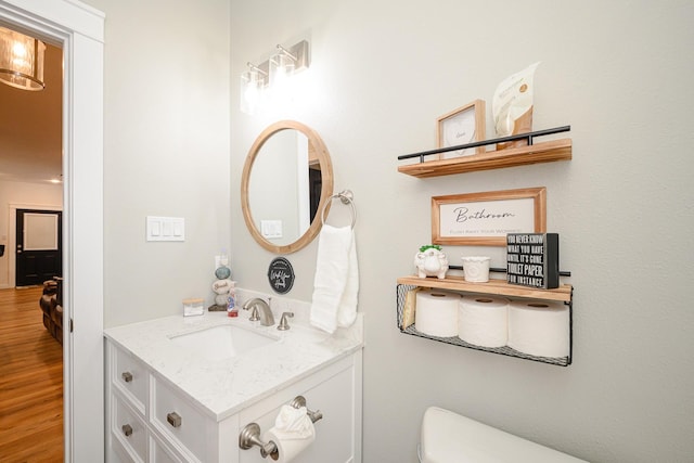 half bath featuring toilet, wood finished floors, and vanity