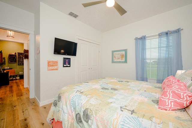 bedroom featuring a closet, visible vents, light wood-style floors, ceiling fan, and baseboards