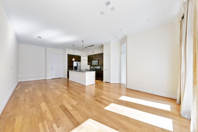 unfurnished living room featuring sink, light hardwood / wood-style floors, and crown molding