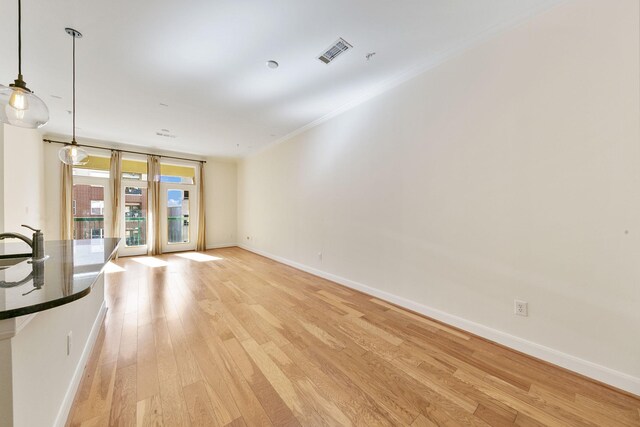 unfurnished living room with sink, light wood-type flooring, crown molding, and floor to ceiling windows