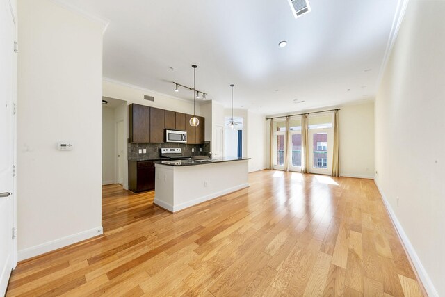 kitchen with decorative backsplash, light wood-type flooring, electric stove, a kitchen island with sink, and dark brown cabinets