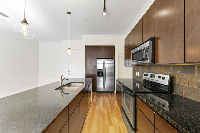 kitchen with backsplash, sink, ornamental molding, appliances with stainless steel finishes, and light hardwood / wood-style floors