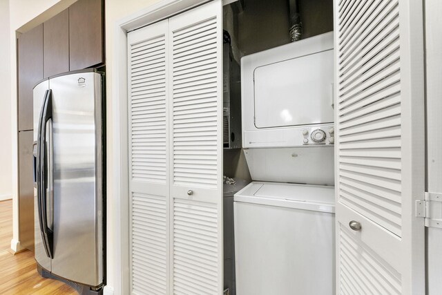 laundry room with light hardwood / wood-style floors and stacked washer and clothes dryer