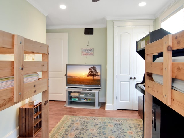 bedroom with a closet, light hardwood / wood-style floors, and crown molding