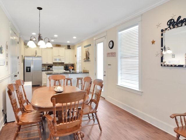 dining space with light hardwood / wood-style floors, a wealth of natural light, an inviting chandelier, and ornamental molding