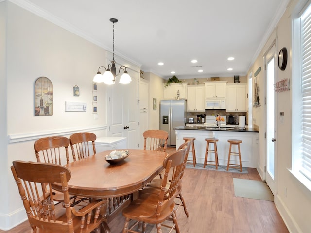 dining room featuring crown molding, an inviting chandelier, and light wood-type flooring