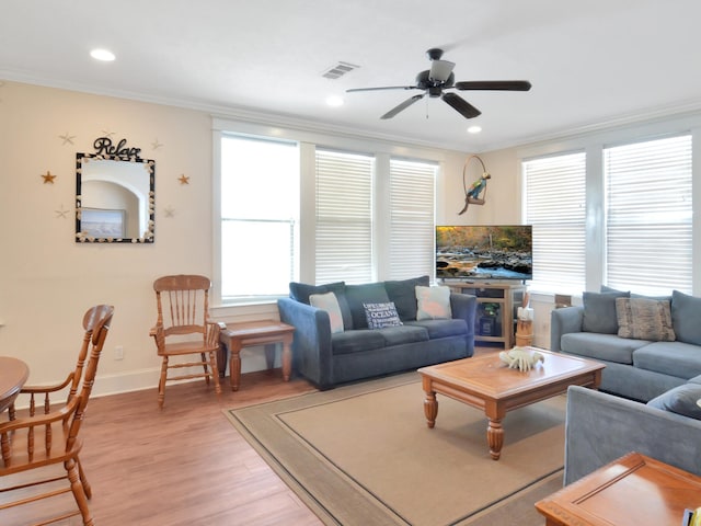 living room with light wood-type flooring, crown molding, and ceiling fan