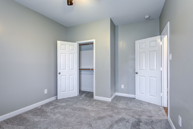 unfurnished bedroom featuring a closet, carpet, a ceiling fan, and baseboards