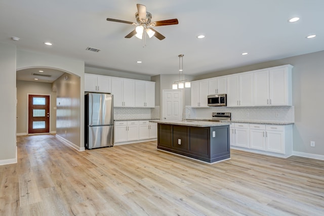 kitchen featuring arched walkways, visible vents, white cabinetry, appliances with stainless steel finishes, and light wood-type flooring