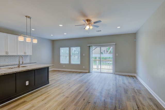 kitchen featuring a sink, visible vents, light wood-style floors, white cabinets, and backsplash