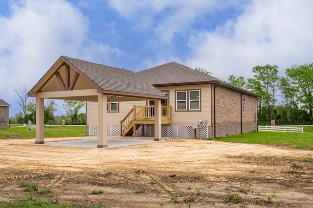 back of property with brick siding, a patio, a shingled roof, stairway, and fence