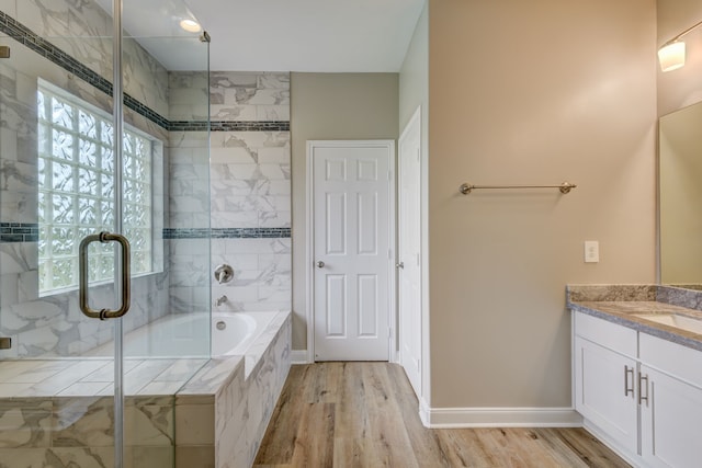 bathroom featuring a tub to relax in, baseboards, wood finished floors, vanity, and a shower stall