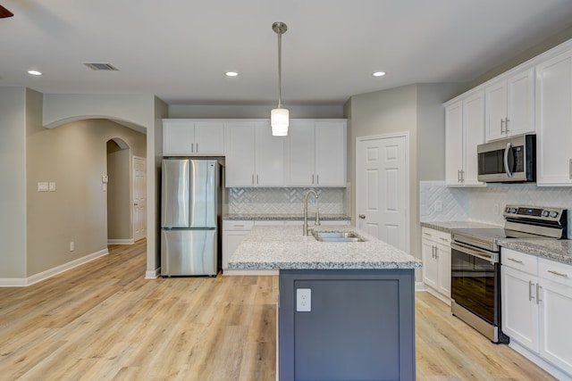 kitchen with visible vents, arched walkways, appliances with stainless steel finishes, light wood-type flooring, and a sink