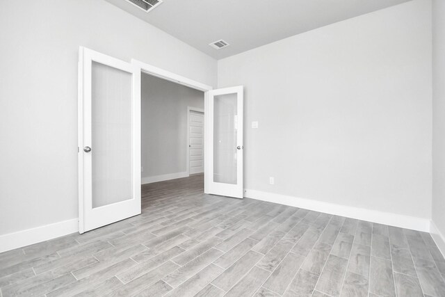 unfurnished bedroom featuring a closet, french doors, and light wood-type flooring