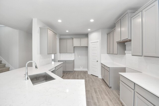 kitchen featuring decorative backsplash, gray cabinets, and sink