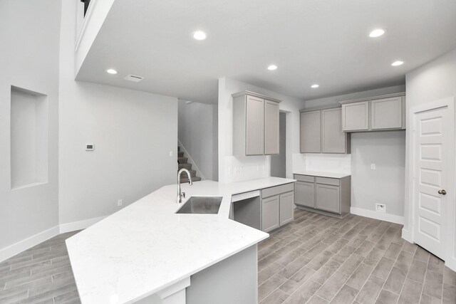 kitchen with gray cabinetry, sink, and light wood-type flooring