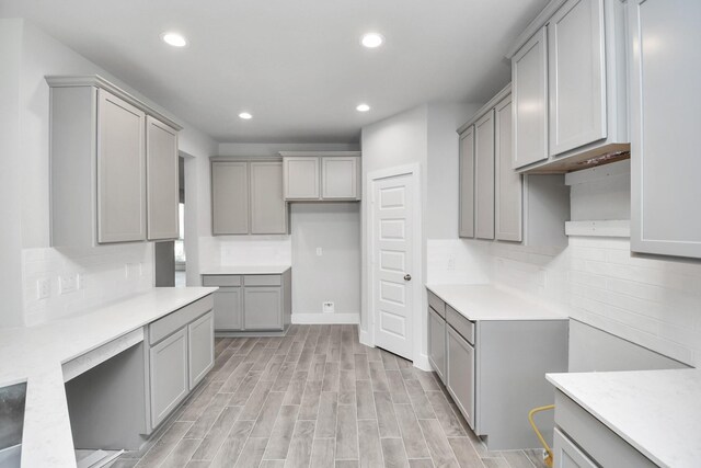 kitchen featuring backsplash, light hardwood / wood-style floors, and gray cabinetry