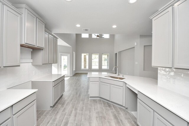 kitchen with ceiling fan, sink, backsplash, light hardwood / wood-style floors, and gray cabinets