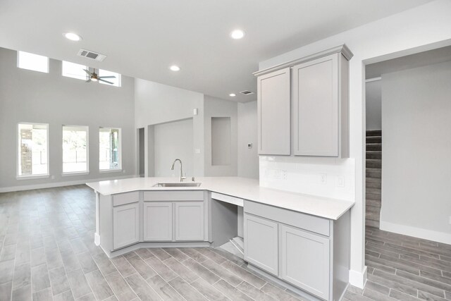 kitchen with kitchen peninsula, ceiling fan, gray cabinetry, and sink