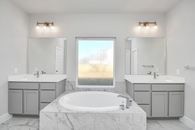 bathroom with tiled bath, a wealth of natural light, and vanity