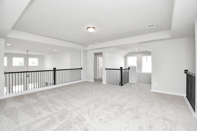 carpeted spare room featuring a wealth of natural light and a tray ceiling