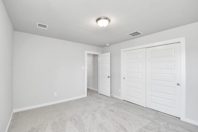 unfurnished bedroom with light carpet and a closet