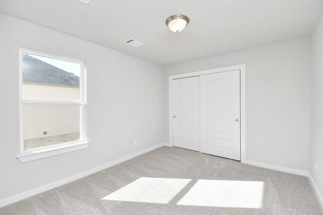 unfurnished bedroom featuring a closet and light colored carpet