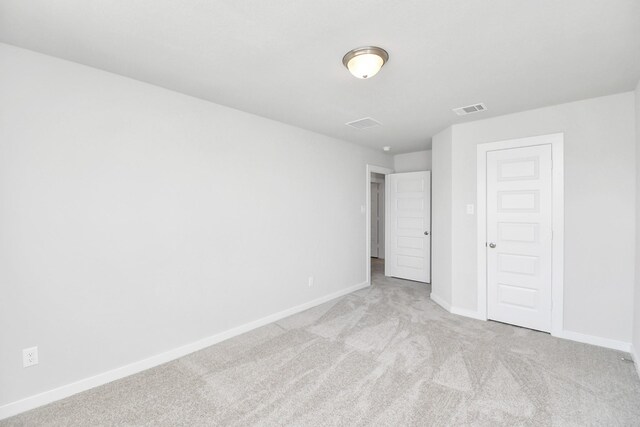 unfurnished bedroom with light colored carpet and a closet