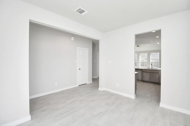 unfurnished room featuring ceiling fan, sink, and light wood-type flooring