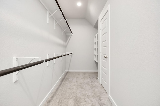 walk in closet with light carpet and vaulted ceiling