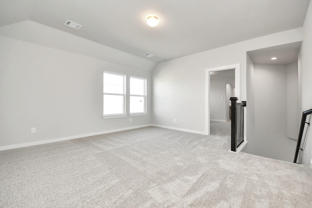 spare room featuring light carpet and vaulted ceiling