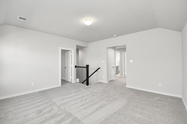 spare room with light colored carpet and vaulted ceiling