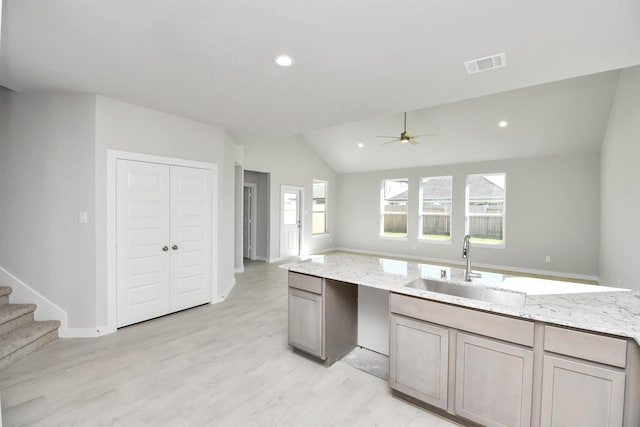 kitchen with light stone countertops, ceiling fan, lofted ceiling, and sink