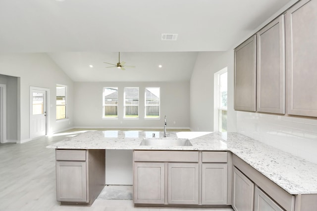 kitchen with tasteful backsplash, ceiling fan, sink, gray cabinets, and lofted ceiling